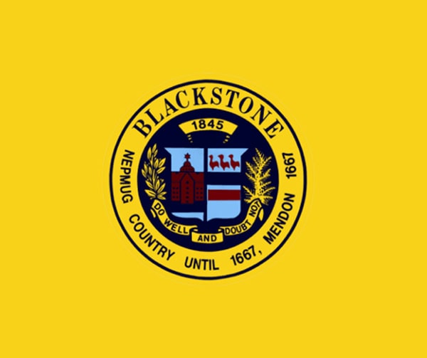 A yellow flag with a circular seal in the center. The seal reads BLACKSTONE and NEPMUG COUNTRY UNTIL 1667, MENDON 1667. Inside is a shield, various symbols, and the motto DO WELL AND DOUBT NOT.